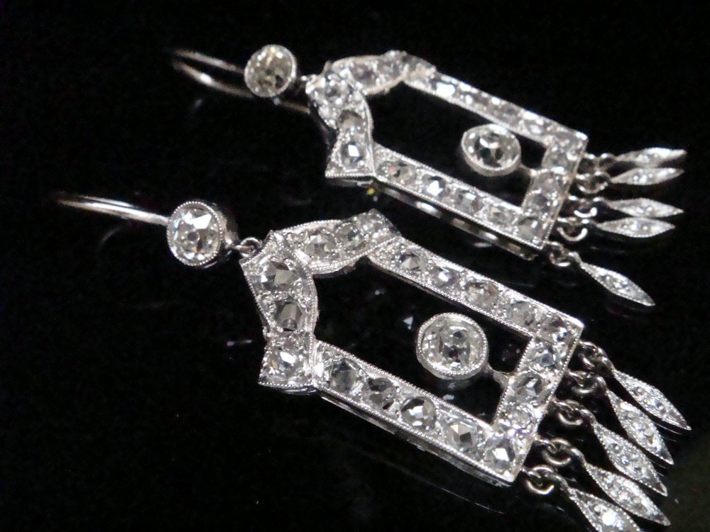 A pair of platinum Art Deco drop earrings featuring openwork geometric frames set with old-cut diamonds and dangling diamond leaf fringes. View IV