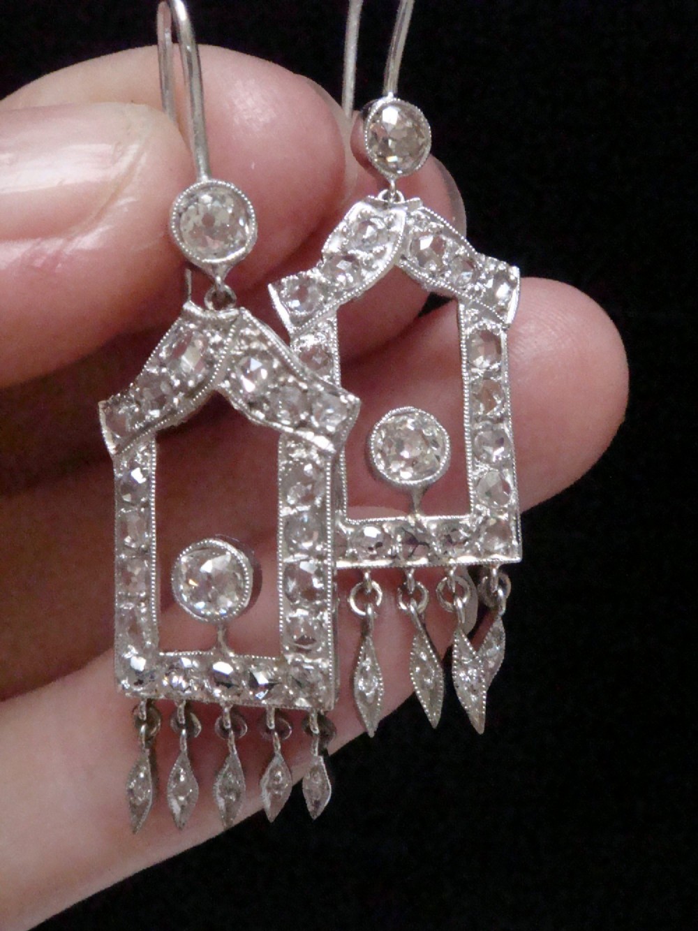 A pair of platinum Art Deco drop earrings featuring openwork geometric frames set with old-cut diamonds and dangling diamond leaf fringes. View VI