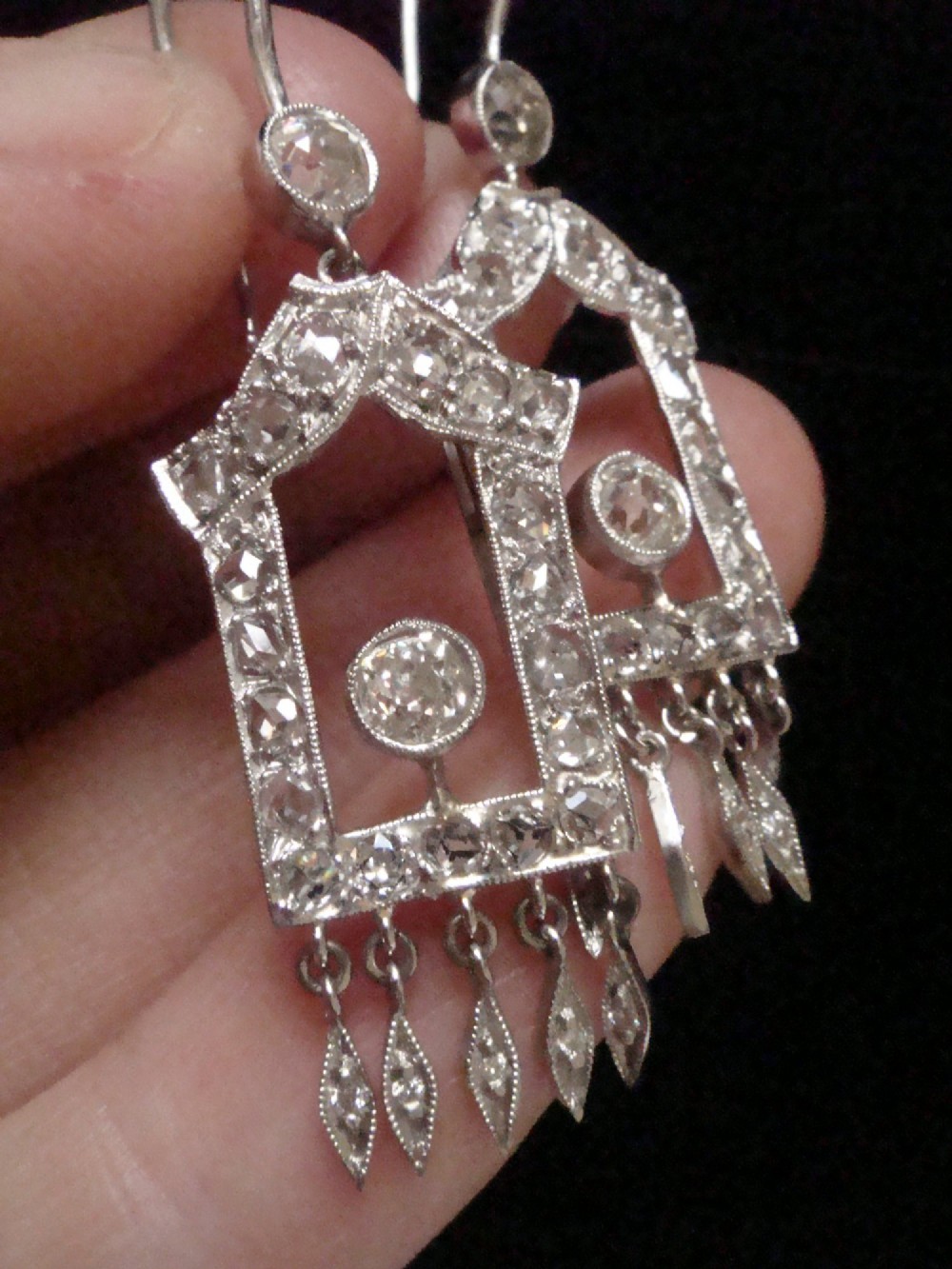 A pair of platinum Art Deco drop earrings featuring openwork geometric frames set with old-cut diamonds and dangling diamond leaf fringes. View VII