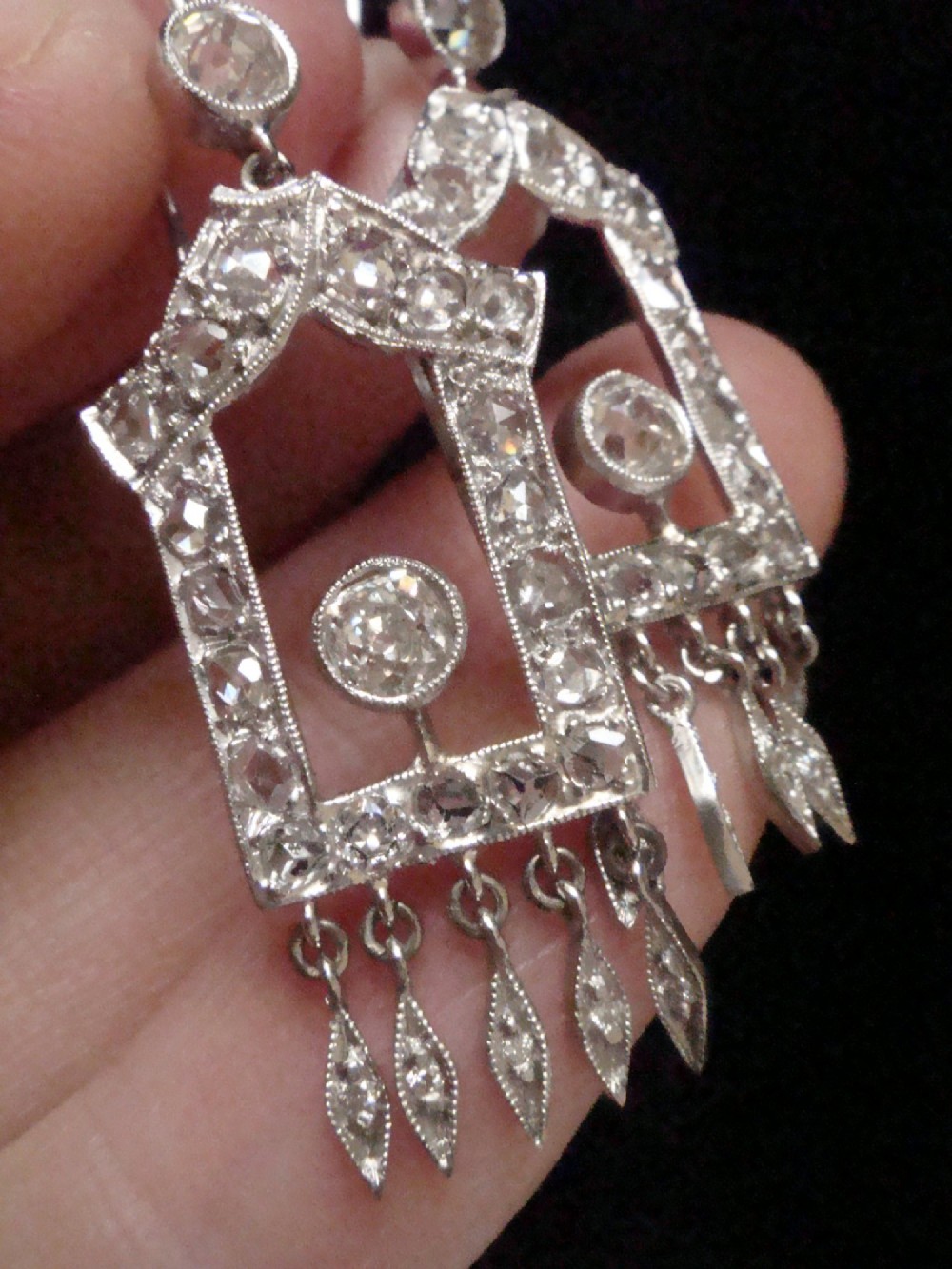 A pair of platinum Art Deco drop earrings featuring openwork geometric frames set with old-cut diamonds and dangling diamond leaf fringes. View VIII