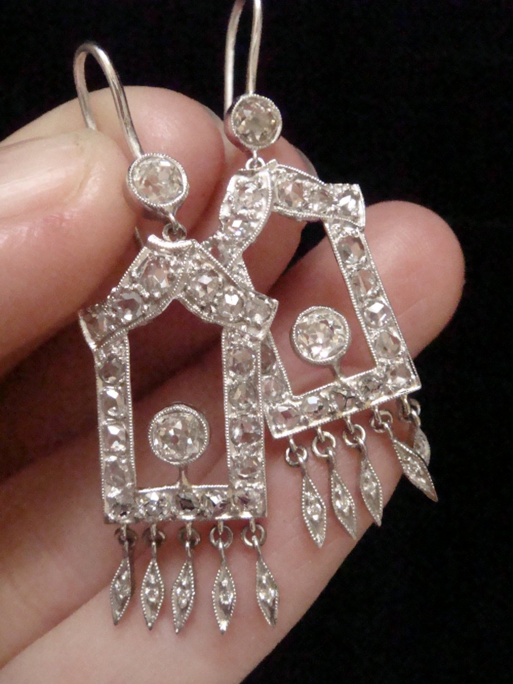 A pair of platinum Art Deco drop earrings featuring openwork geometric frames set with old-cut diamonds and dangling diamond leaf fringes. View IX