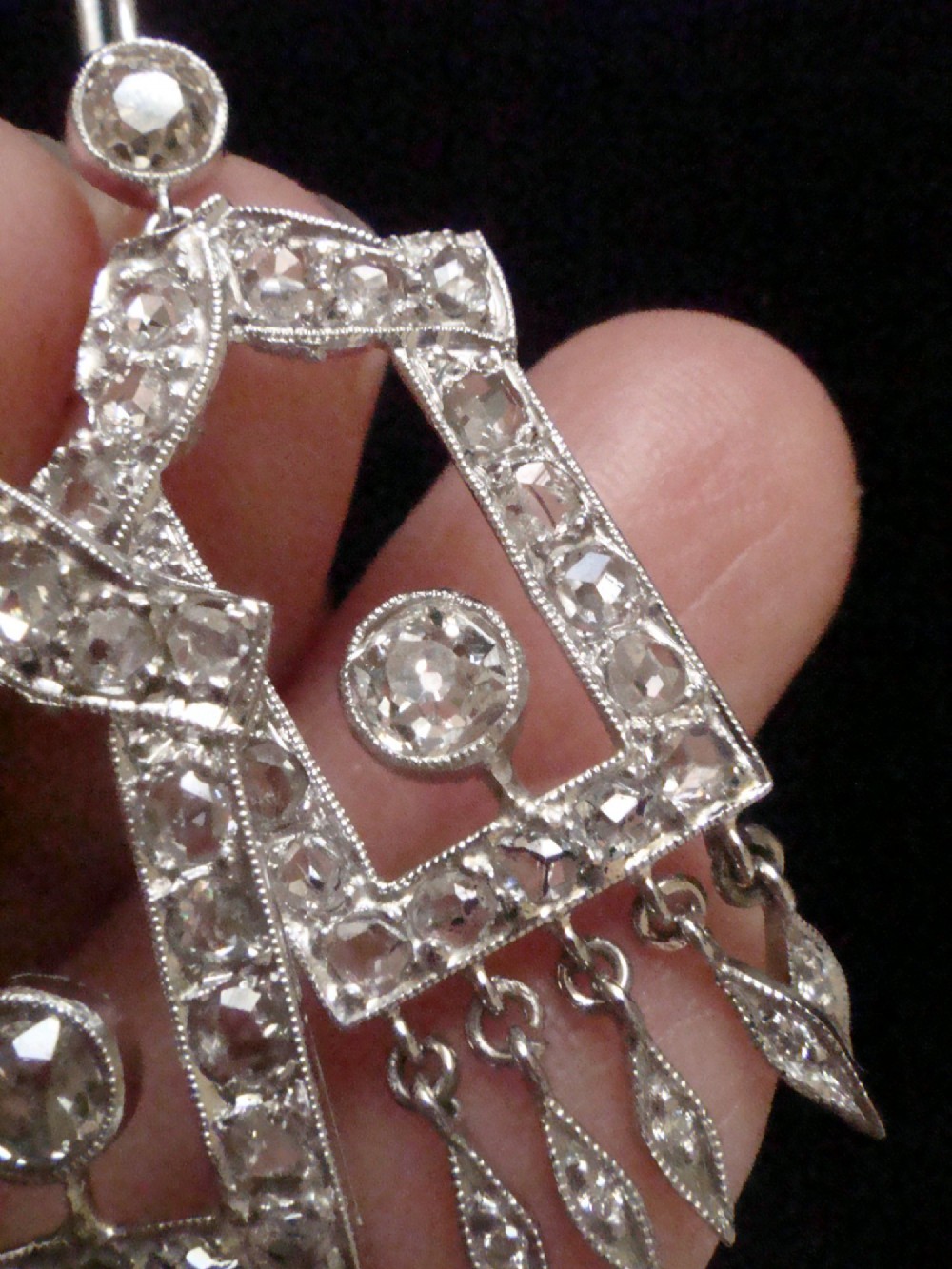 A pair of platinum Art Deco drop earrings featuring openwork geometric frames set with old-cut diamonds and dangling diamond leaf fringes. View X
