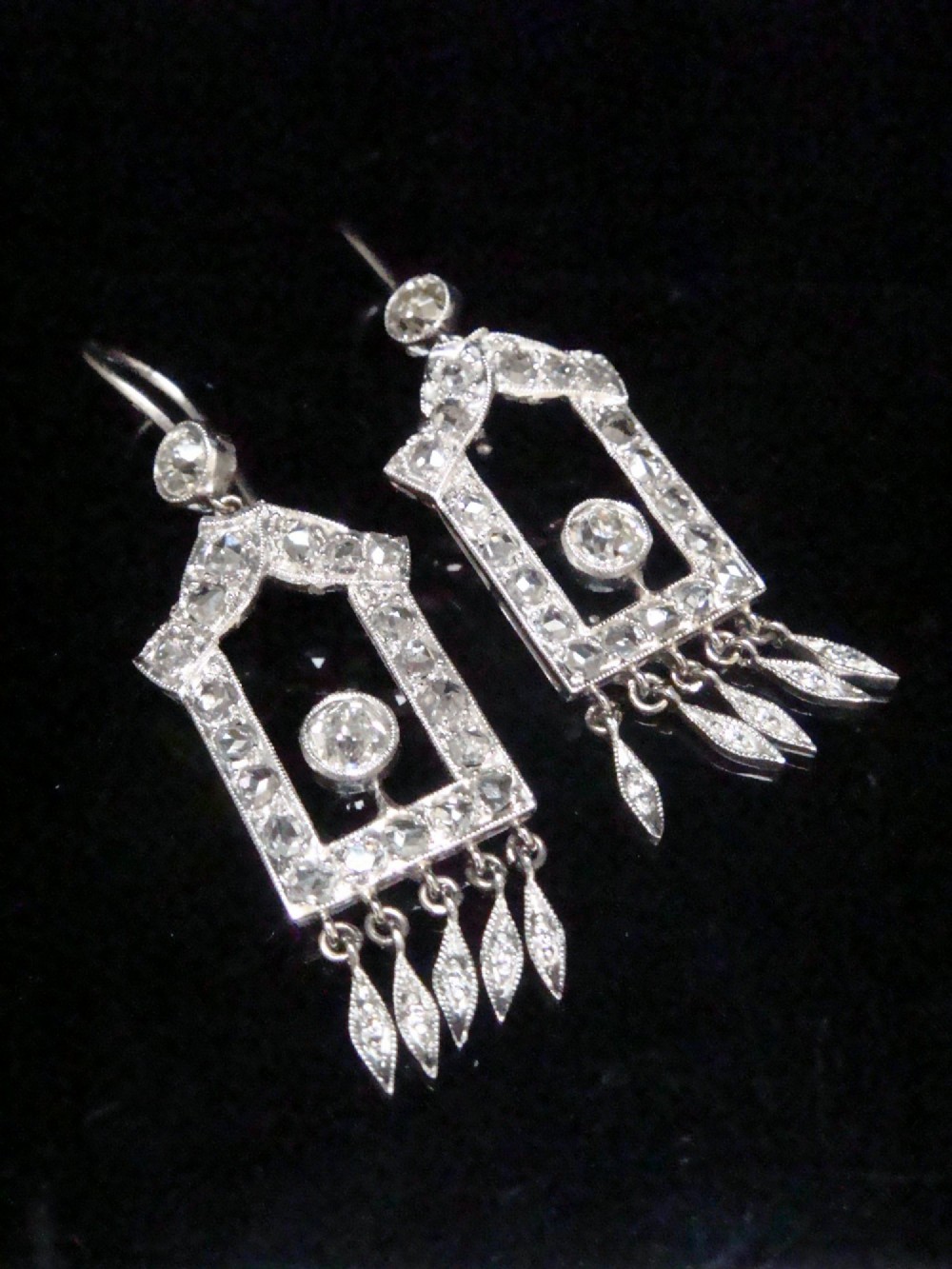A pair of platinum Art Deco drop earrings featuring openwork geometric frames set with old-cut diamonds and dangling diamond leaf fringes. View II
