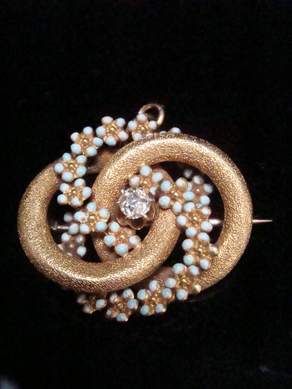 Victorian 18ct textured gold lovers knot brooch and pendant featuring light blue enamelled forget-me-not flowers and a central solitaire diamond.