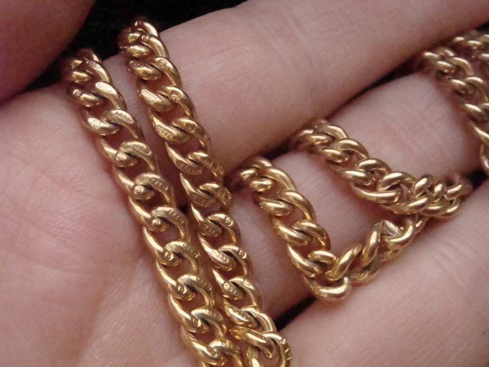 An Edwardian 9ct yellow gold curb link chain featuring a swivel clip clasp and individual hallmark stamps on each link. View V