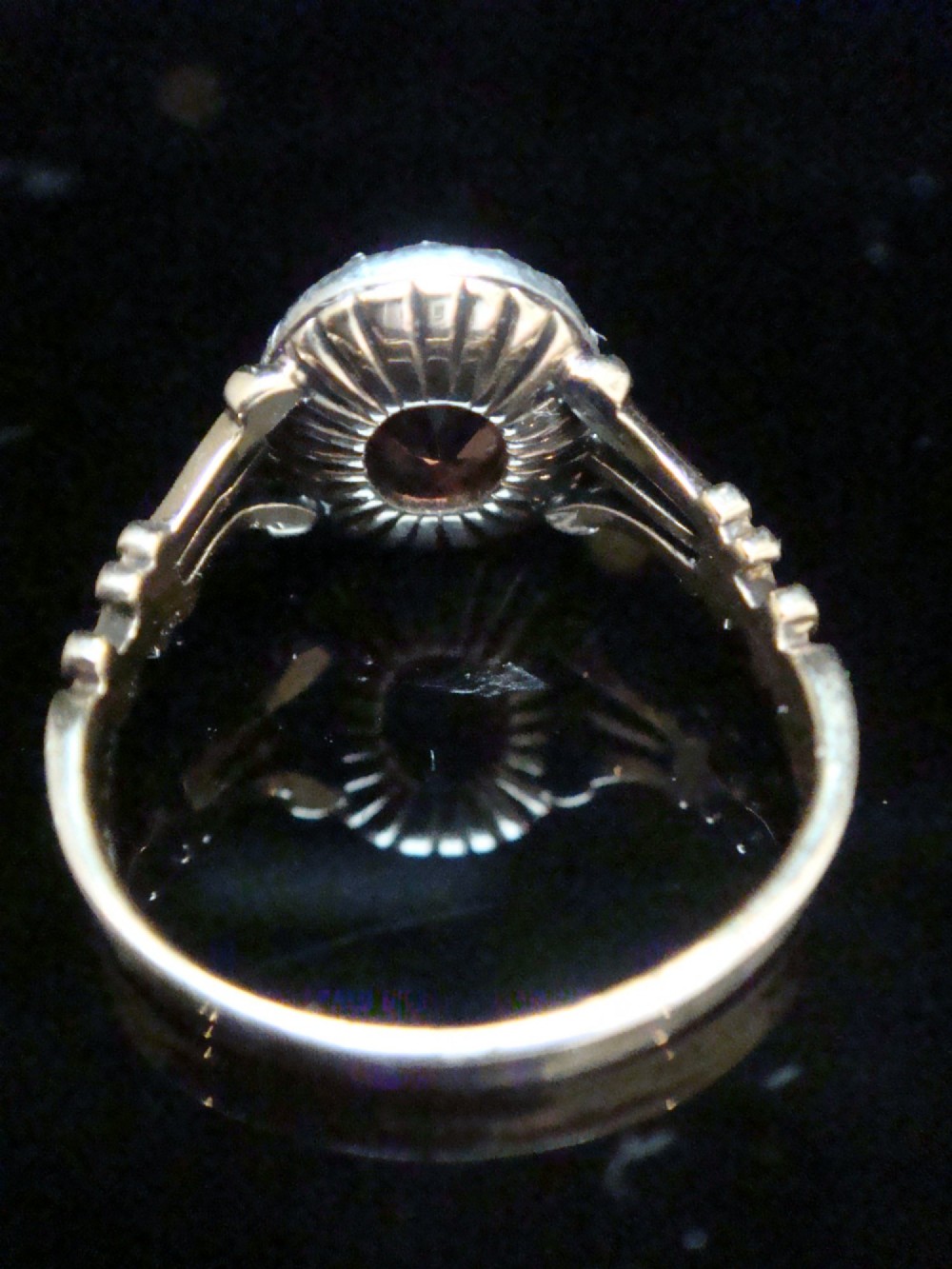 An Edwardian 18ct gold ring with a central cushion-cut peach tourmaline surrounded by a halo of old-cut diamonds and bifurcated shoulders. View II