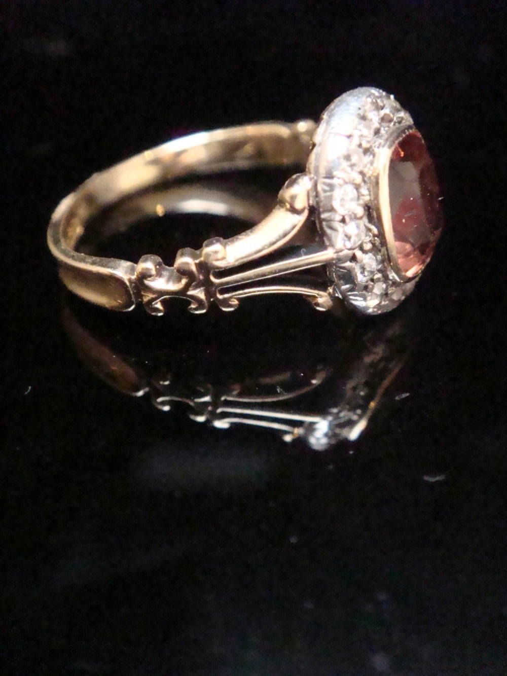 An Edwardian 18ct gold ring with a central cushion-cut peach tourmaline surrounded by a halo of old-cut diamonds and bifurcated shoulders. View III