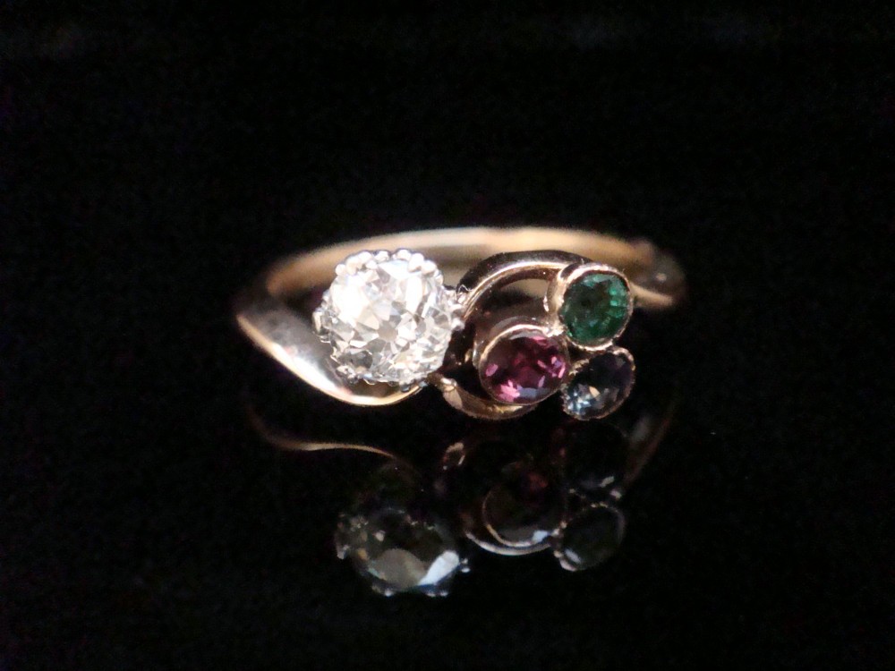 An Edwardian 18ct gold swirl ring featuring a brilliant diamond set alongside a cluster of sapphire, emerald, and pink tourmaline gemstones. View II