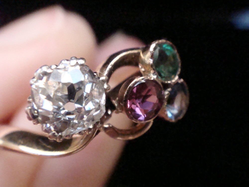An Edwardian 18ct gold swirl ring featuring a brilliant diamond set alongside a cluster of sapphire, emerald, and pink tourmaline gemstones. View IV