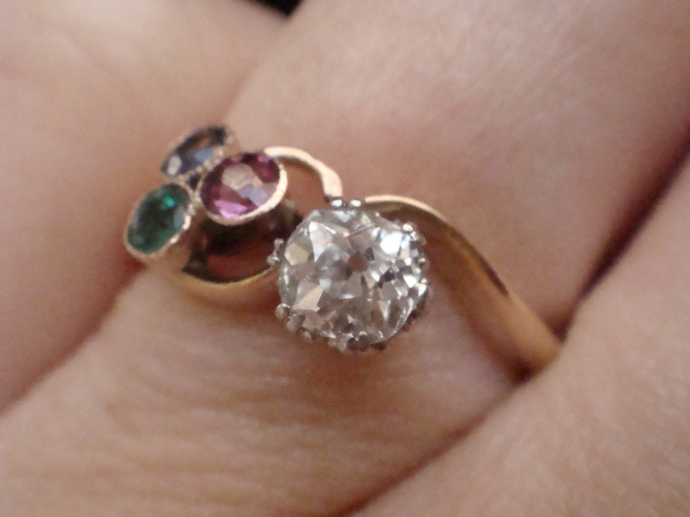 An Edwardian 18ct gold swirl ring featuring a brilliant diamond set alongside a cluster of sapphire, emerald, and pink tourmaline gemstones. View VII