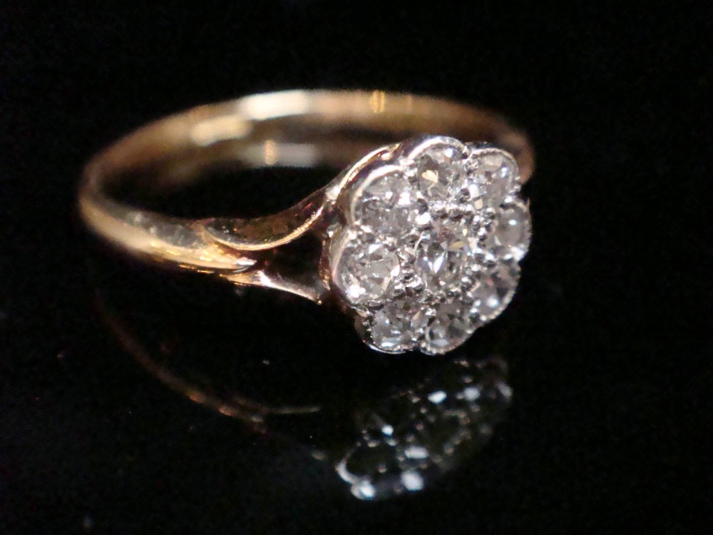 An Edwardian diamond cluster ring featuring a flower-shaped platinum head set on a yellow gold band. View II