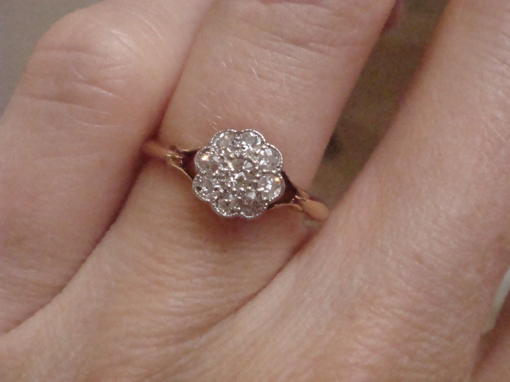 An Edwardian diamond cluster ring featuring a flower-shaped platinum head set on a yellow gold band. View IV