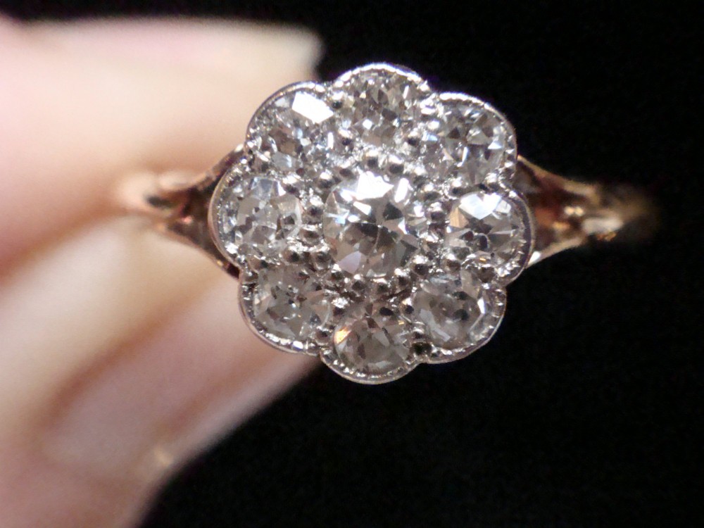 An Edwardian diamond cluster ring featuring a flower-shaped platinum head set on a yellow gold band. View VII