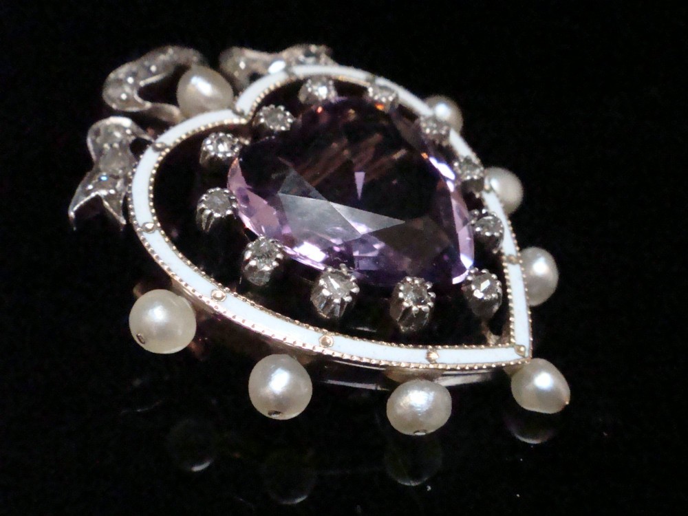 An Edwardian heart-shaped gold pendant featuring a central purple gemstone framed by diamonds, white guilloche enamel, and small natural pearls. View VII