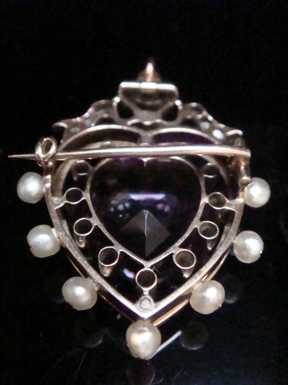 An Edwardian heart-shaped gold pendant featuring a central purple gemstone framed by diamonds, white guilloche enamel, and small natural pearls. View VIII