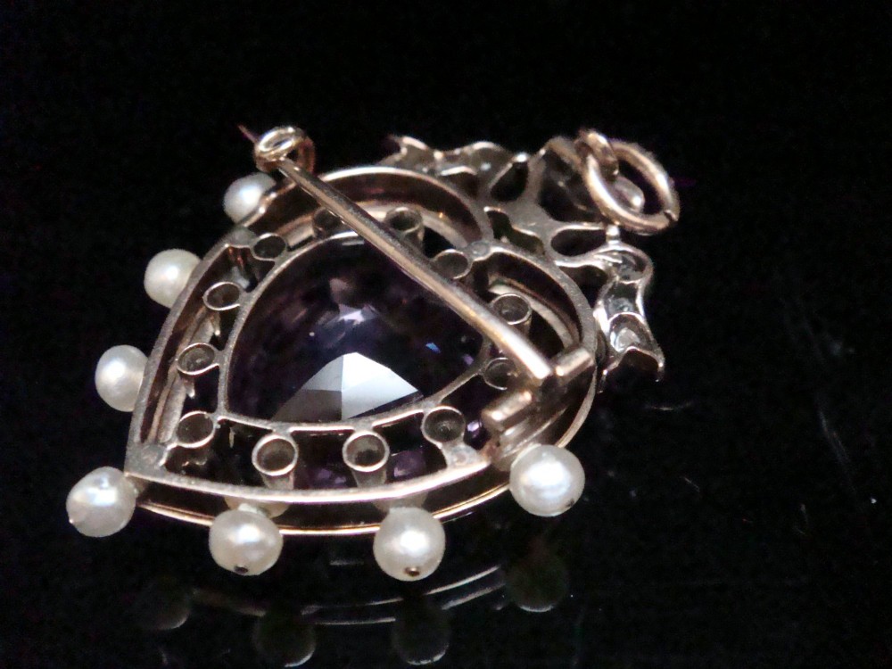 An Edwardian heart-shaped gold pendant featuring a central purple gemstone framed by diamonds, white guilloche enamel, and small natural pearls. View IX