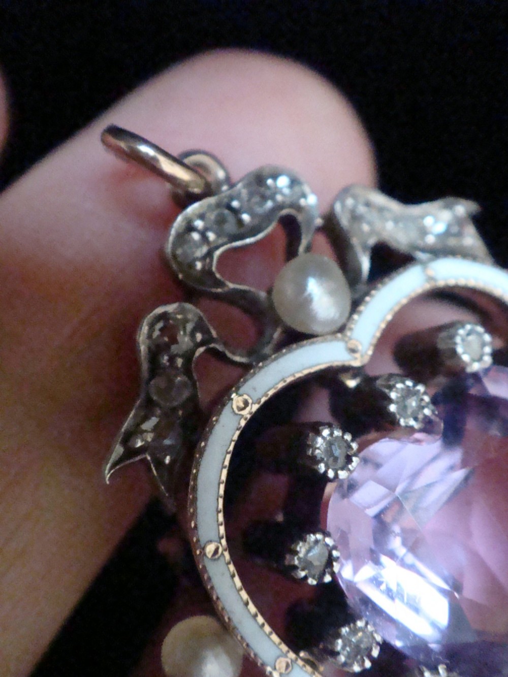 An Edwardian heart-shaped gold pendant featuring a central purple gemstone framed by diamonds, white guilloche enamel, and small natural pearls. View V