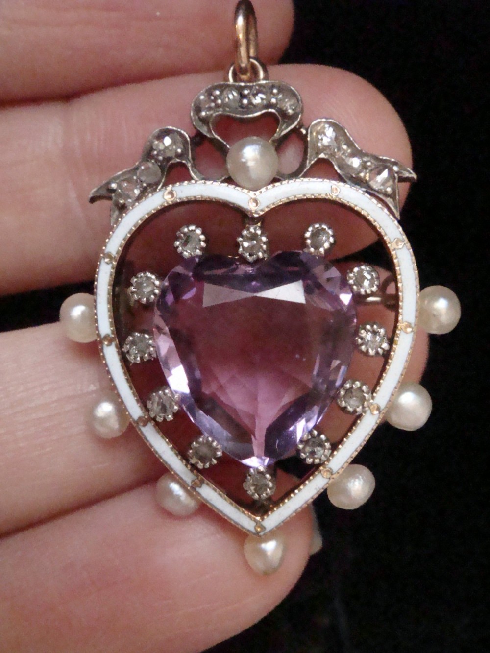 An Edwardian heart-shaped gold pendant featuring a central purple gemstone framed by diamonds, white guilloche enamel, and small natural pearls. View III