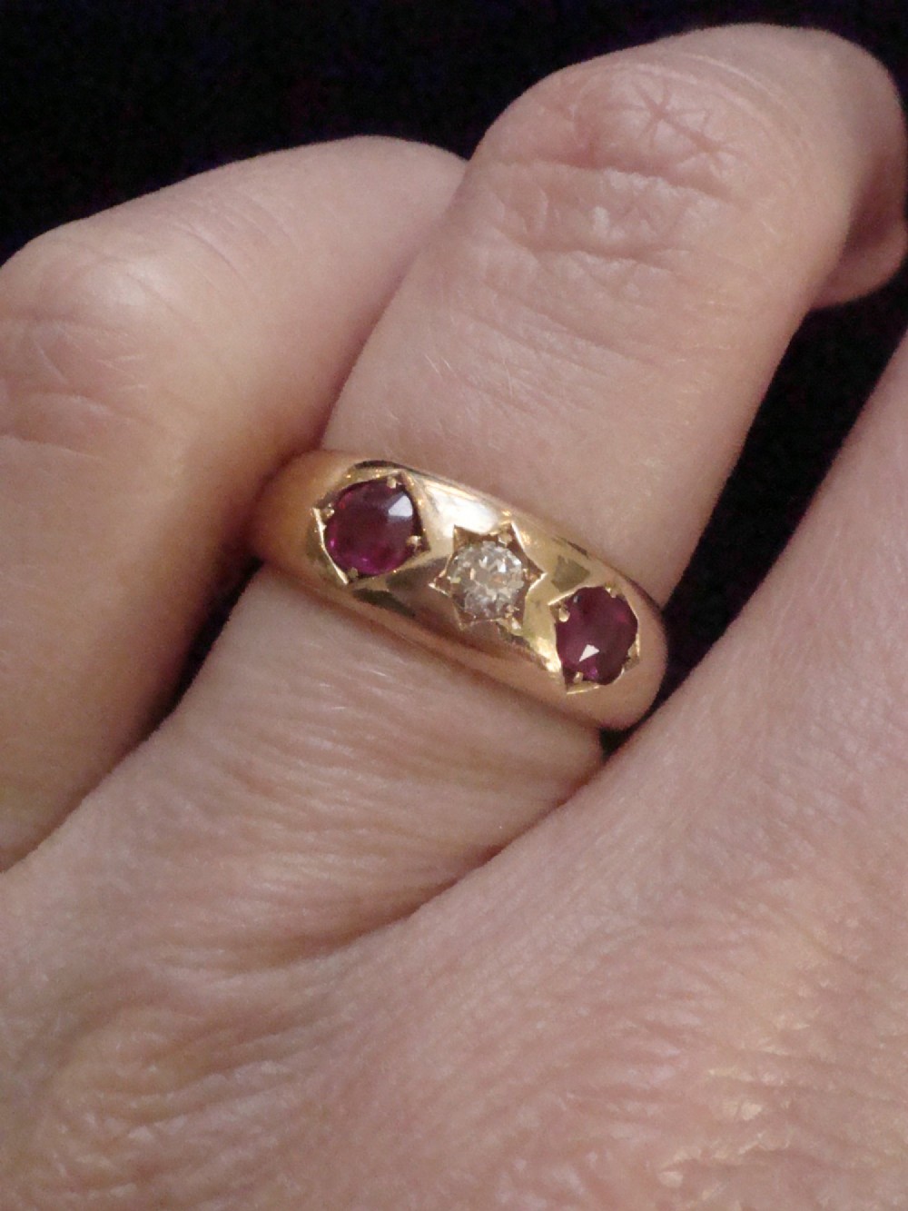 An Edwardian 18ct yellow gold gypsy band ring set with a central old cut diamond flanked by two rubies in star-shaped recessed mountings. View IV