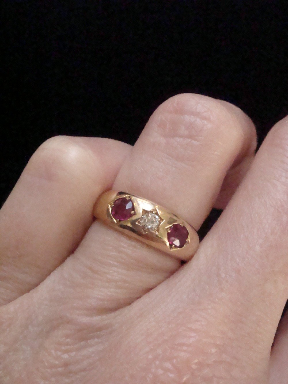 An Edwardian 18ct yellow gold gypsy band ring set with a central old cut diamond flanked by two rubies in star-shaped recessed mountings. View V