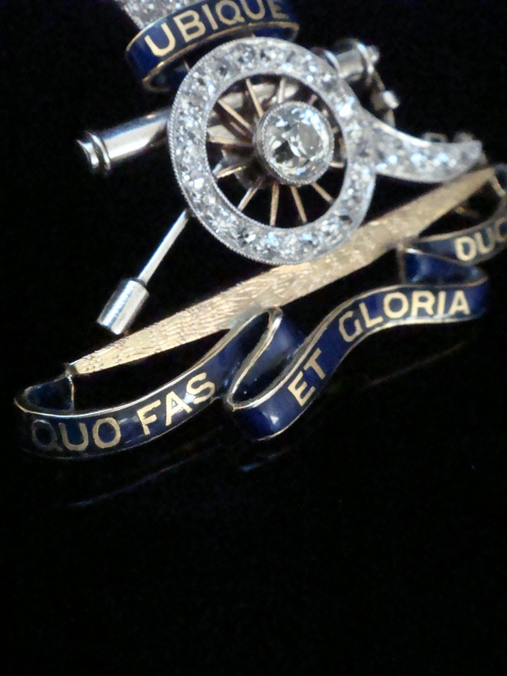 An Edwardian platinum and gold Royal Artillery badge brooch featuring blue guilloche enamel mottos and diamond settings. View V