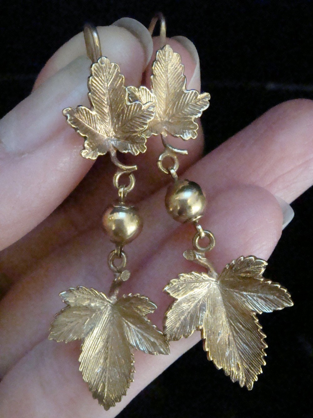 A pair of Edwardian 9ct yellow gold drop earrings featuring detailed leaf motifs suspended from small gold beads and shepherd hooks. View IV
