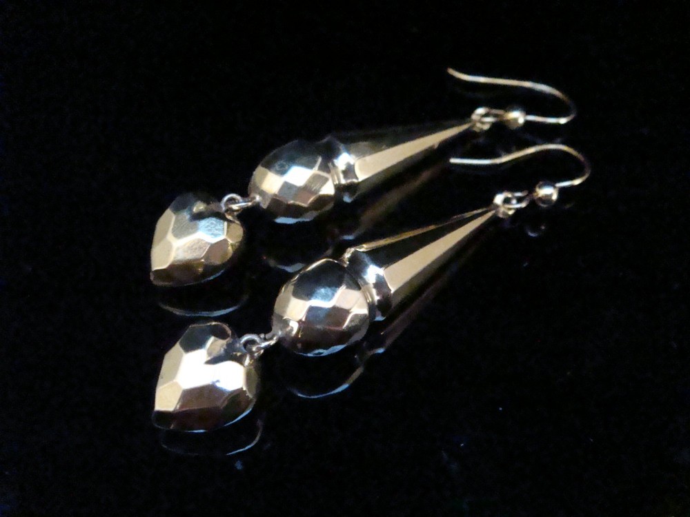 A pair of Edwardian 9ct yellow gold drop earrings featuring geometric faceted tapered bars and faceted heart pendants hanging from hook wires.