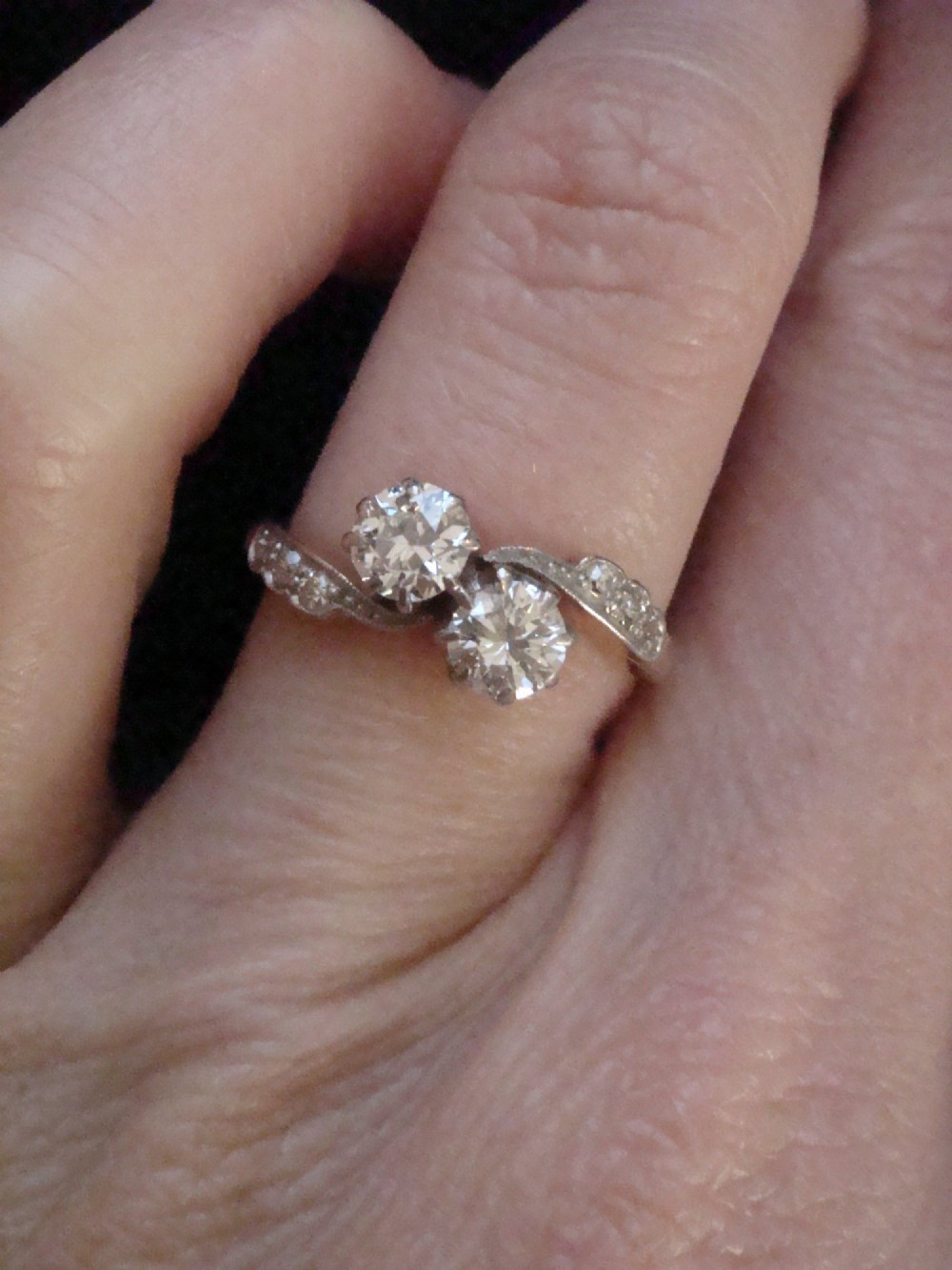 An Edwardian two-stone diamond crossover ring set in platinum and yellow gold with accent diamonds along the curved shoulders. View V