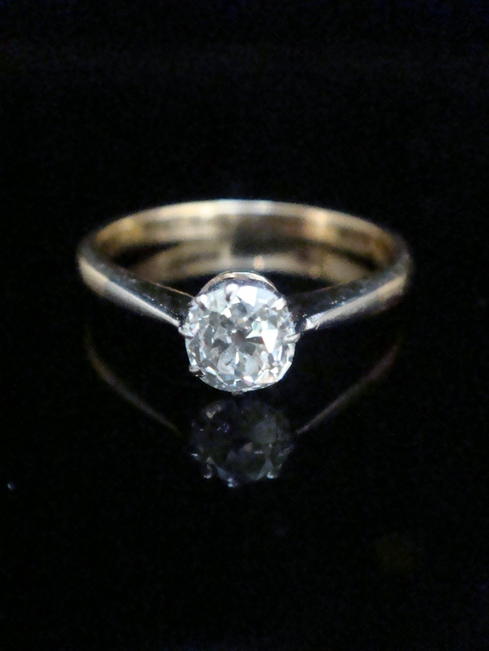 An Edwardian single stone diamond ring featuring a single central diamond set in a platinum claw setting on an eighteen carat gold band.