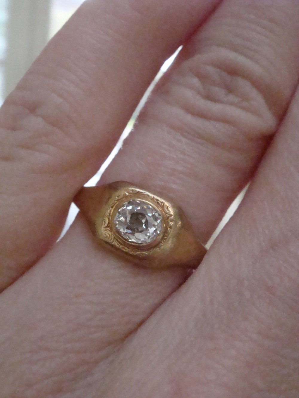 A Victorian 18ct yellow gold gypsy ring set with a single old cut diamond in a flush rubover bezel with hand engraving. View VII