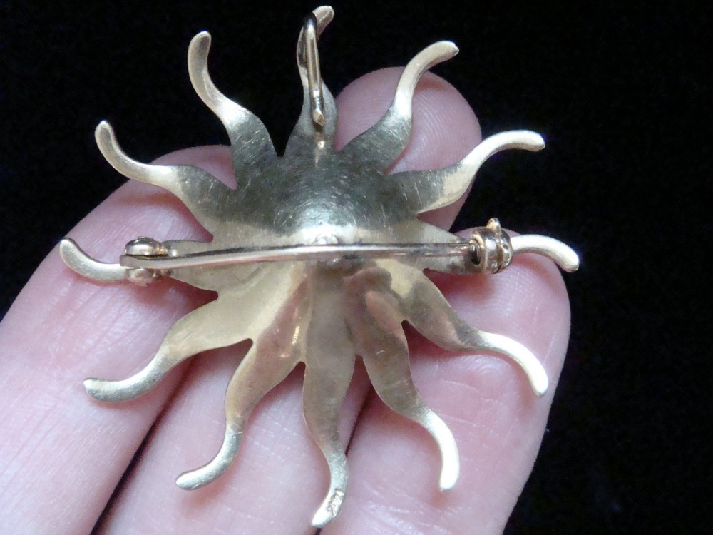 An antique 14ct yellow gold starburst pendant brooch decorated with seed pearl rays around a central star setting with a sapphire and rose-cut diamonds. View IV