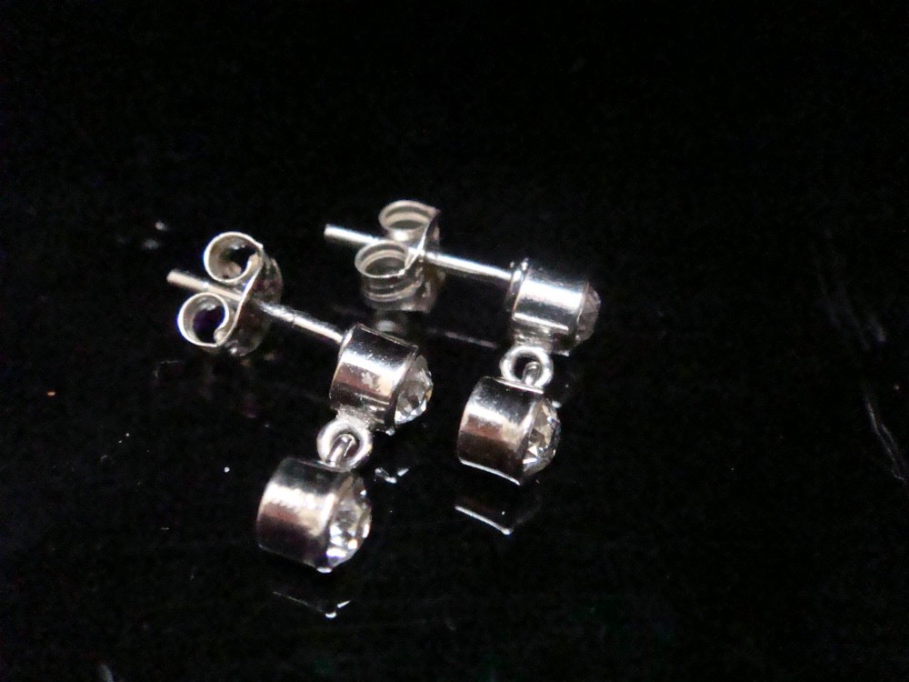 Pair of Edwardian 18ct white gold drop earrings featuring rubover bezel-set old cut diamonds. View VI