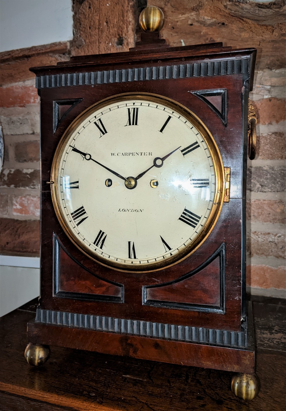 A 19th-century mahogany fusee bracket clock with a brass finial, brass ball feet, fluted wood trim, and a white dial displaying Roman numerals. View II