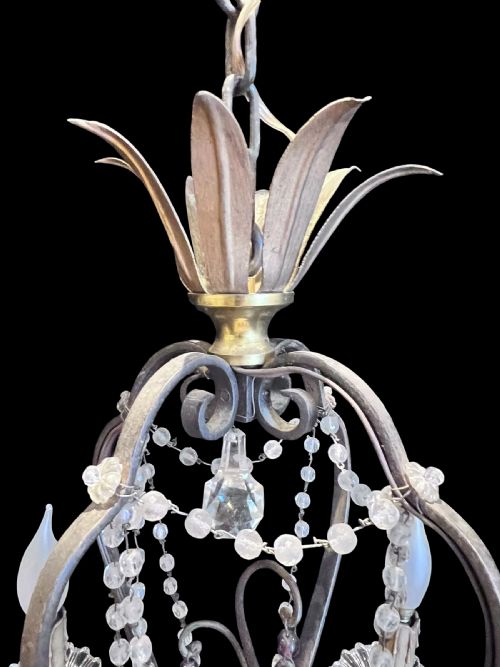 fig 1. A four-arm French antique chandelier featuring a dark metal cage frame adorned with clear and amethyst-tinted glass crystal beads and teardrop pendants.