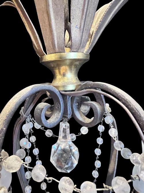 fig 1. A four-arm French antique chandelier featuring a dark metal cage frame adorned with clear and amethyst-tinted glass crystal beads and teardrop pendants.