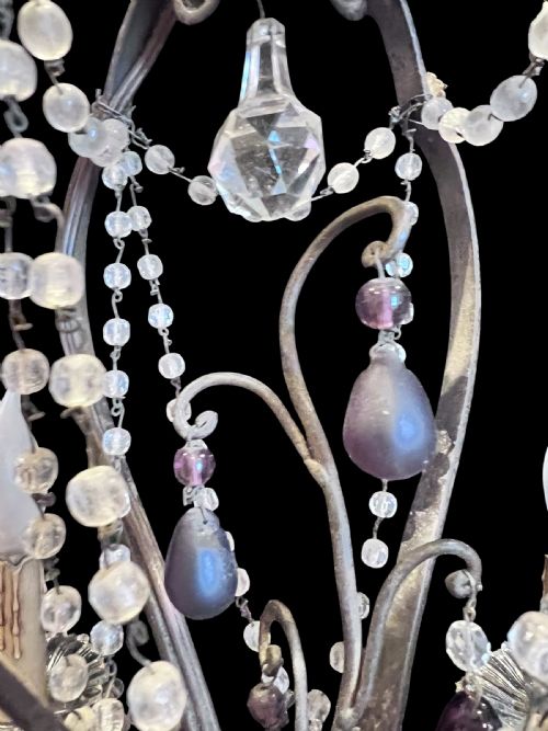 fig 4. A four-arm French antique chandelier featuring a dark metal cage frame adorned with clear and amethyst-tinted glass crystal beads and teardrop pendants.