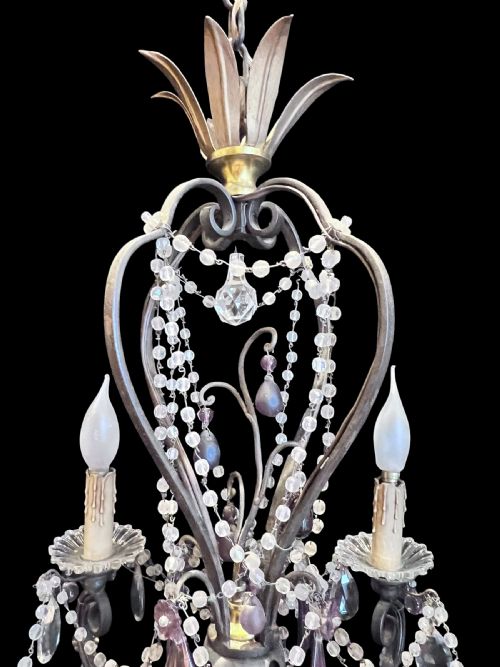 fig 5. A four-arm French antique chandelier featuring a dark metal cage frame adorned with clear and amethyst-tinted glass crystal beads and teardrop pendants.