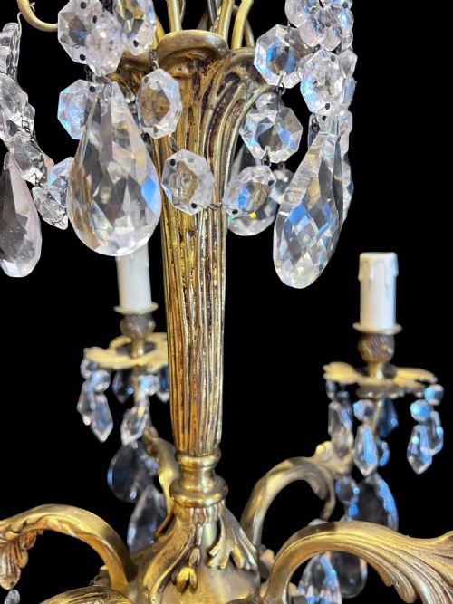 fig 2. A six-light French ormolu ceiling chandelier decorated with clear faceted crystal drops, candle-shaped light sockets, and a central fluted column.