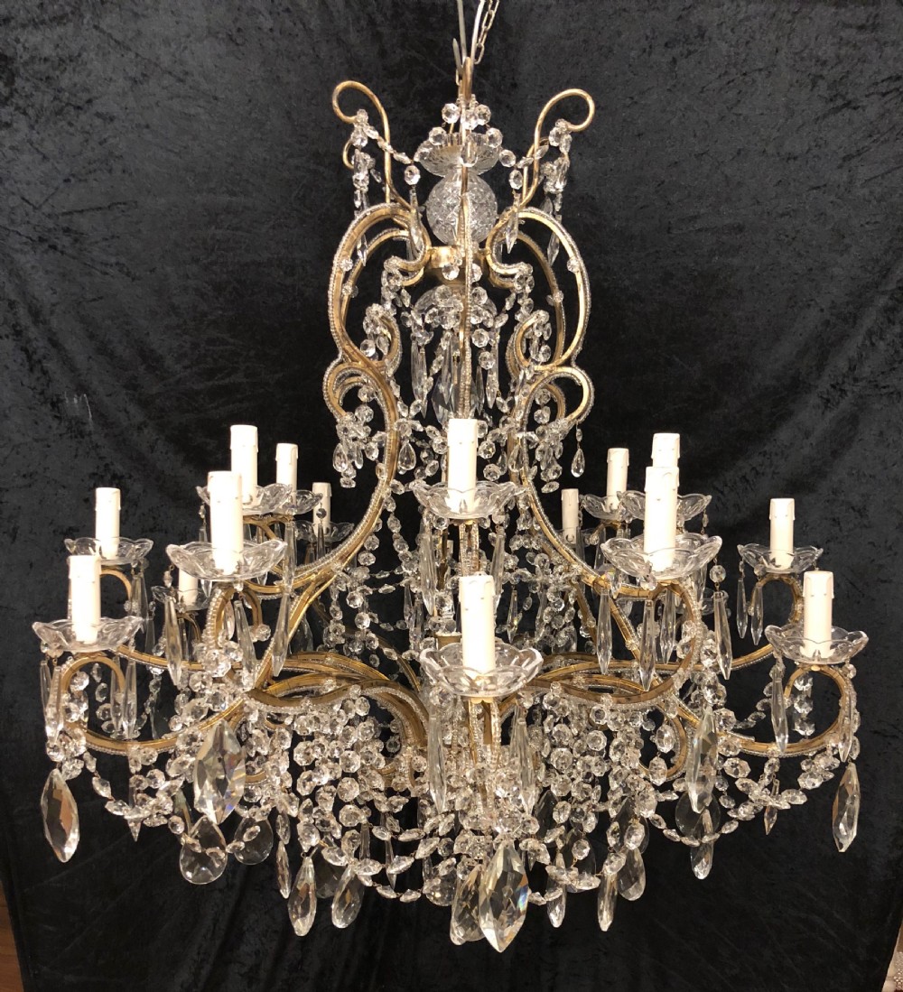 A large Italian Florentine eighteen light chandelier featuring a gilt scroll frame hung with cut crystal drops and glass bead strands.