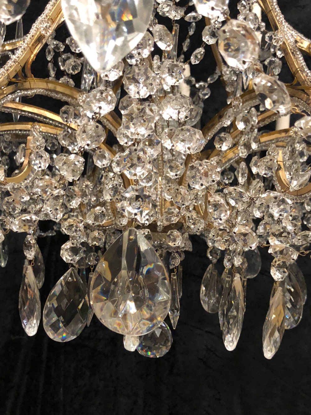 A large Italian Florentine eighteen light chandelier featuring a gilt scroll frame hung with cut crystal drops and glass bead strands. View VI