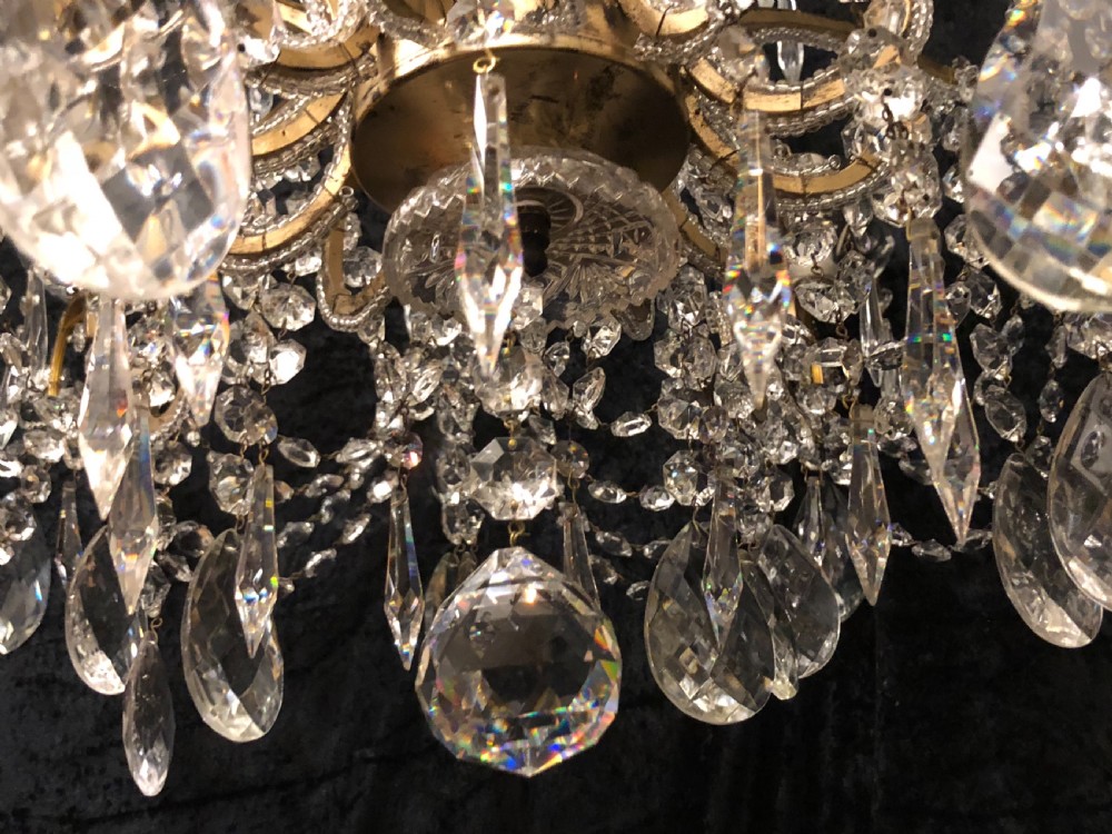 A large Italian Florentine eighteen light chandelier featuring a gilt scroll frame hung with cut crystal drops and glass bead strands. View X