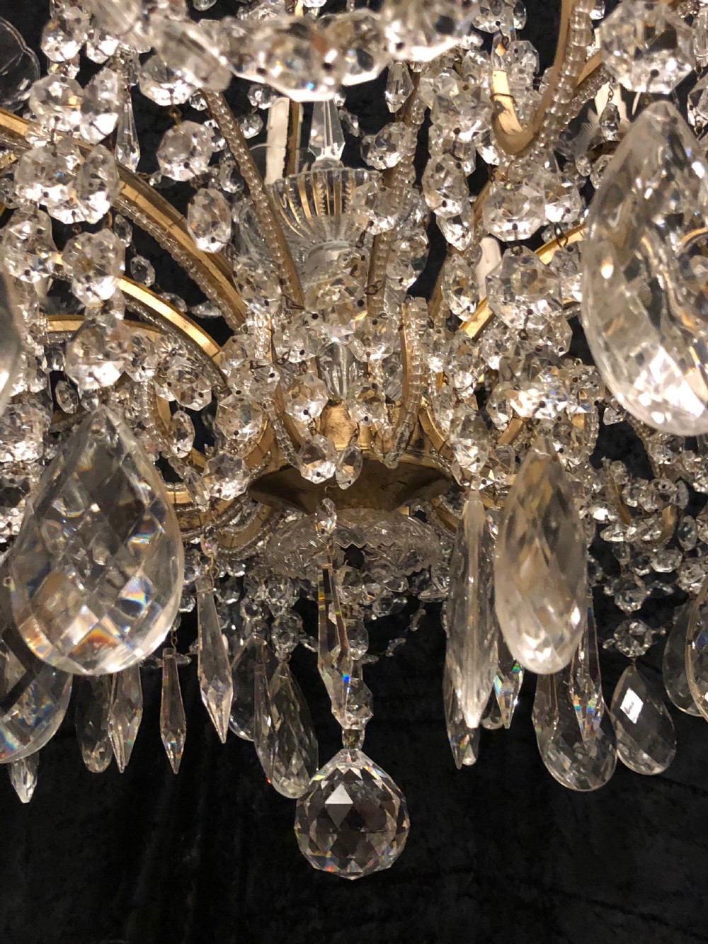 A large Italian Florentine eighteen light chandelier featuring a gilt scroll frame hung with cut crystal drops and glass bead strands. View XII
