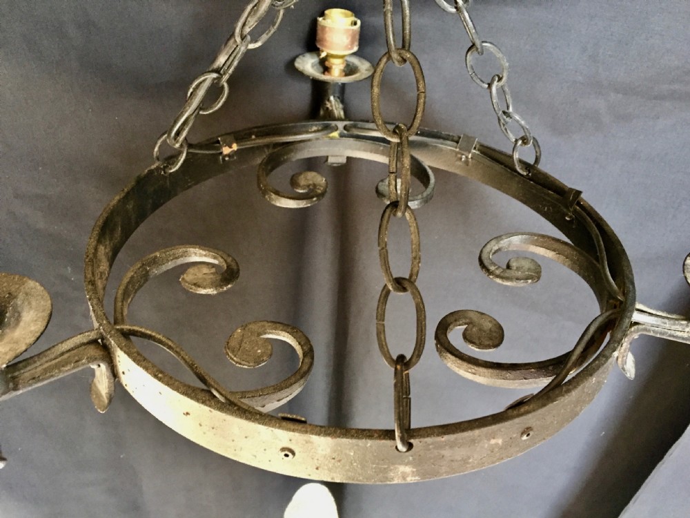 A three-light black wrought iron wagon wheel chandelier with scroll motifs, central suspension chains, and candle-style socket holders. View II
