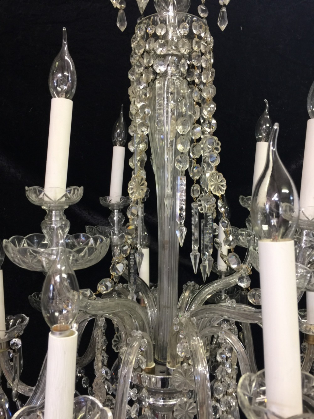 A multi-armed antique cut glass chandelier featuring cascading crystal drops, scalloped bobeches, and white candle sleeves. View IV