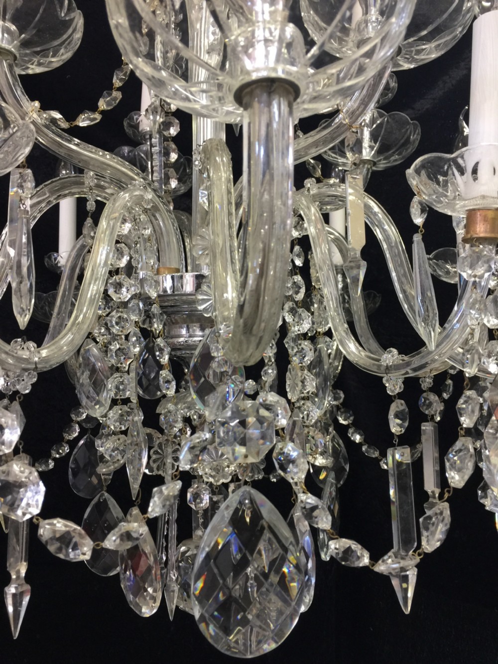 A multi-armed antique cut glass chandelier featuring cascading crystal drops, scalloped bobeches, and white candle sleeves. View VI