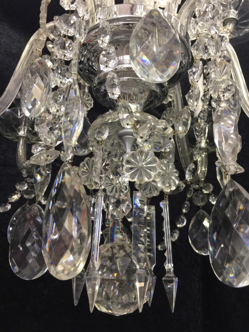 A multi-armed antique cut glass chandelier featuring cascading crystal drops, scalloped bobeches, and white candle sleeves. View VII