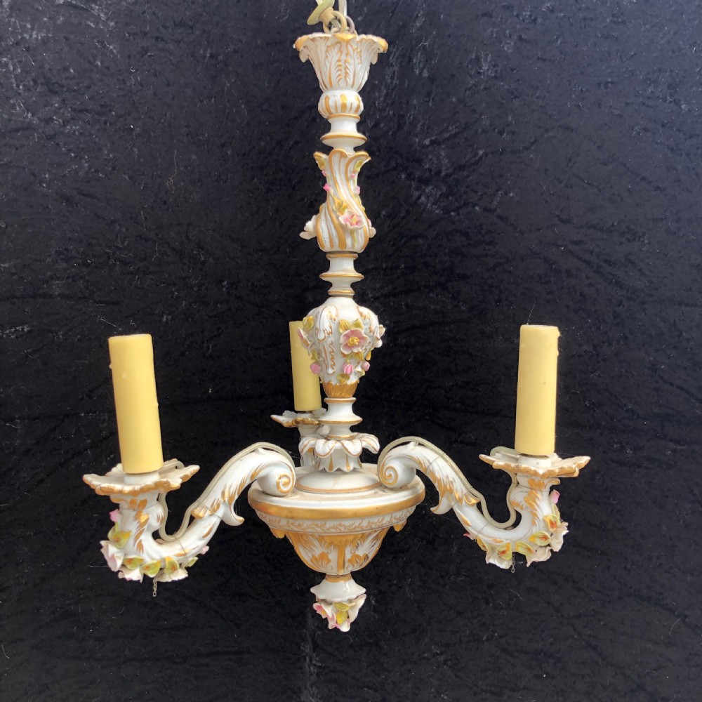 A three-arm Capodimonte porcelain chandelier with white glaze, gold scroll detailing, applied ceramic flowers, and candle-style bulb holders.