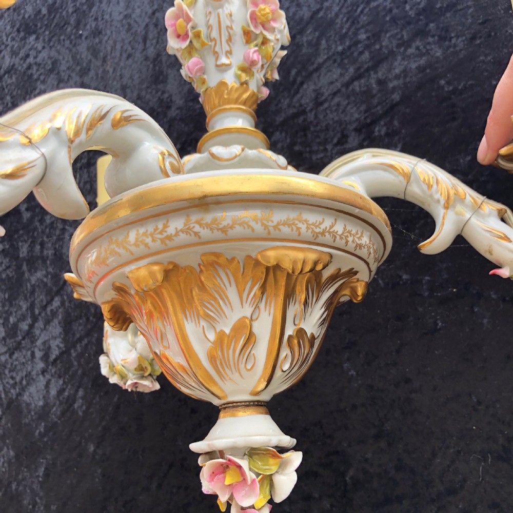 A three-arm Capodimonte porcelain chandelier with white glaze, gold scroll detailing, applied ceramic flowers, and candle-style bulb holders. View VII