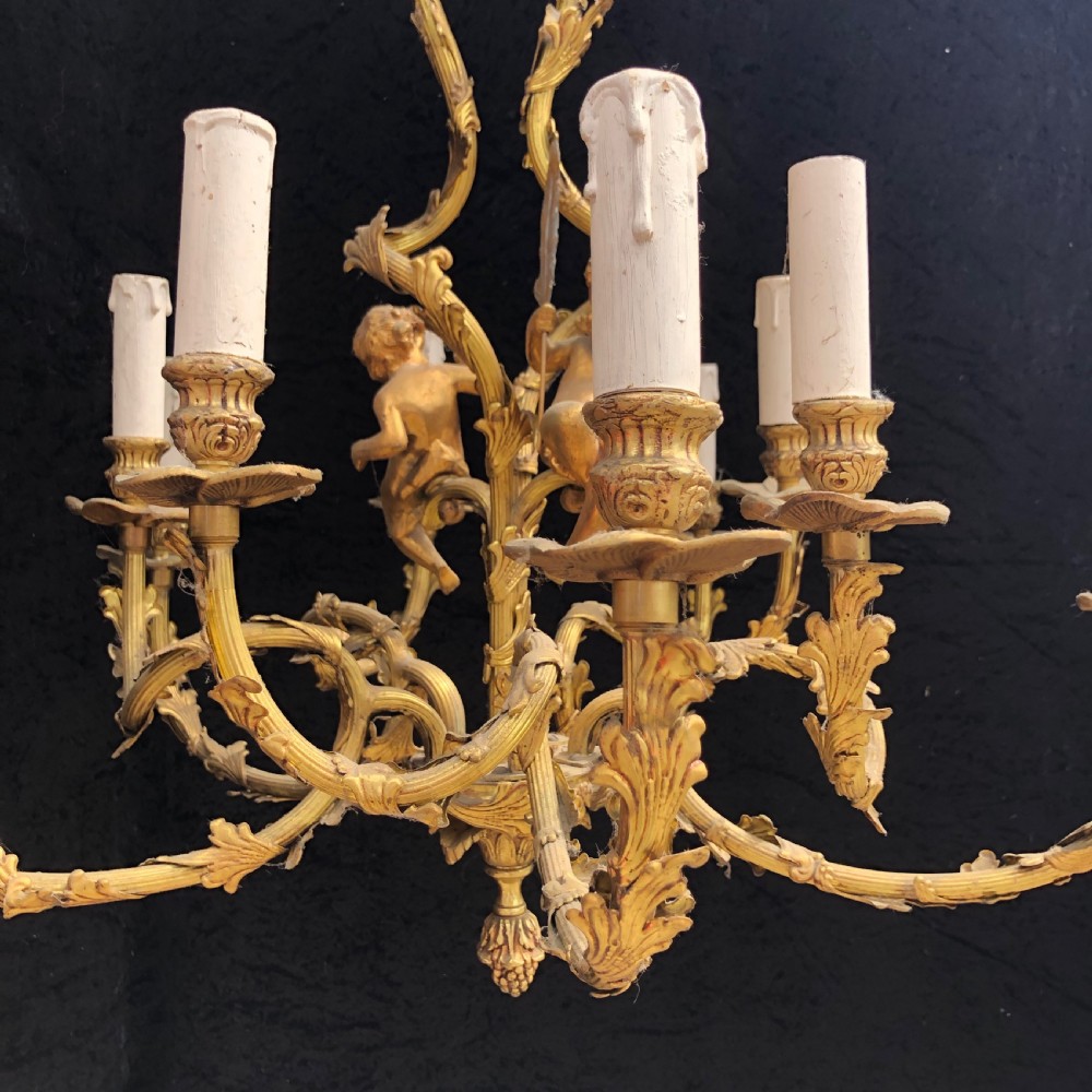 A French Rococo style ten-light gilt bronze chandelier featuring sculpted cherubs, scrolled acanthus leaf arms, and white candle sleeves. View VIII