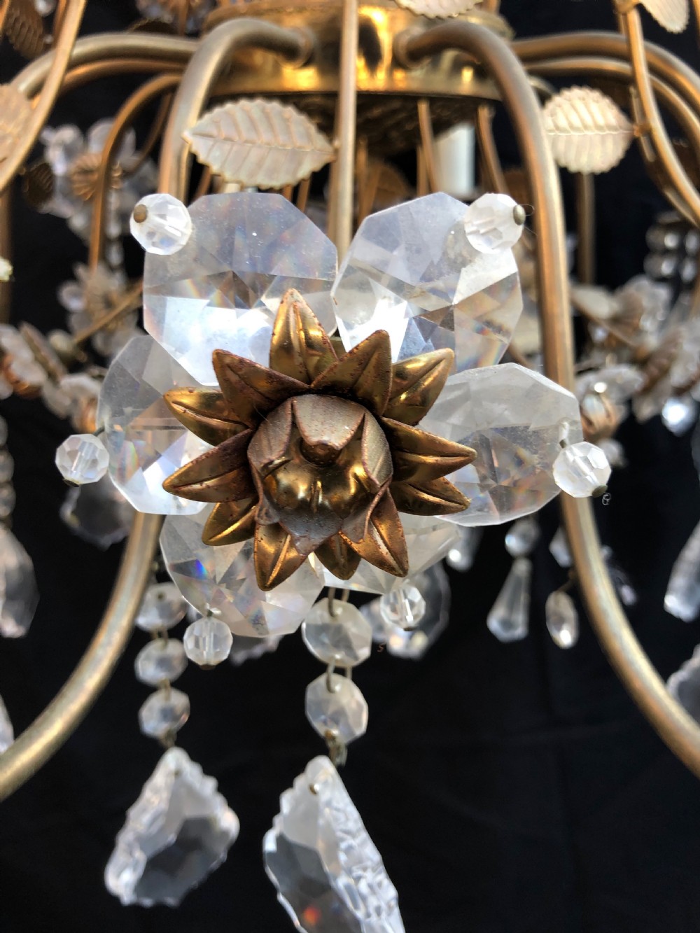 A twelve-light Florentine chandelier crafted from gilt metal featuring crystal flower heads, leaf details, and faceted crystal drops hanging from curved arms. View VI